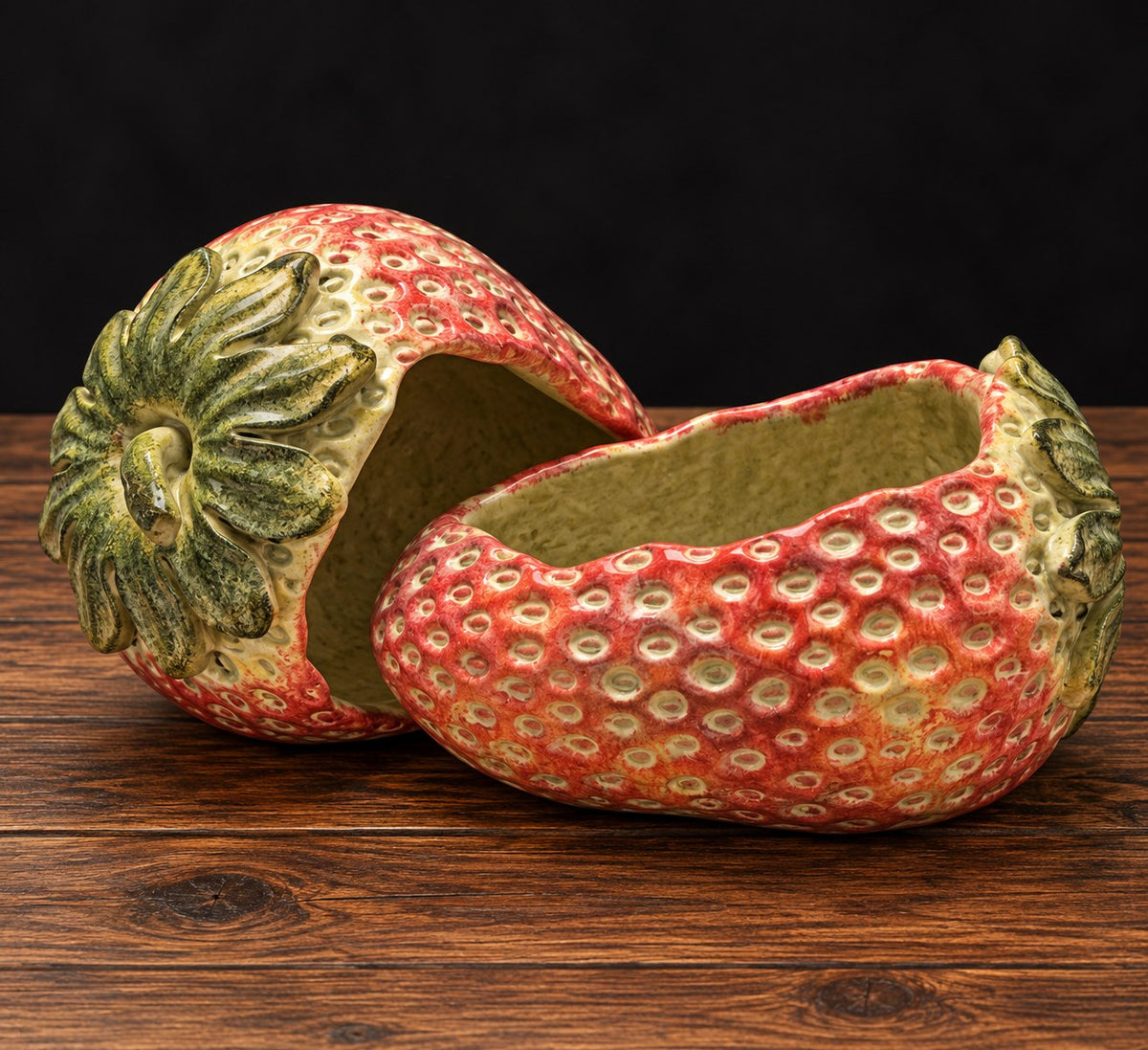 Fresa decorativa de cemento pintada a mano, en rojo con hojas verdes, sobre mesa de madera