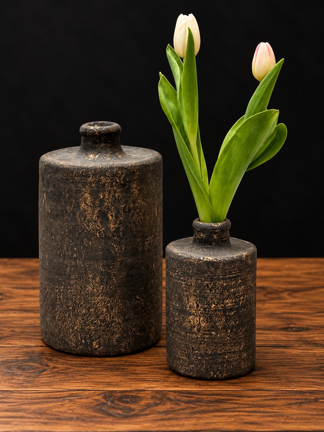 Dos botellas decorativas rústicas en gris antracita con toques dorados, grande y pequeña, sobre mesa de madera
