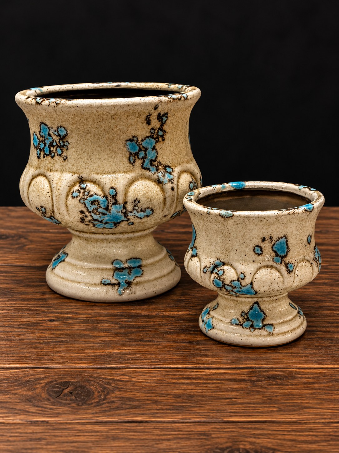 Dos copas de cerámica esmaltada en tono arena con manchas azules, grande y pequeña, sobre mesa de madera