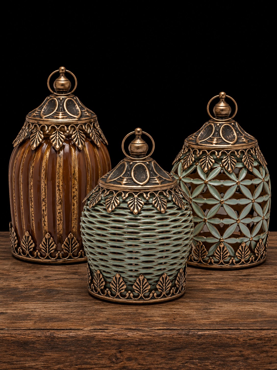 Tres faroles decorativos con acabado dorado envejecido, uno rayado caramelo y dos verdes, sobre mesa de madera rústica