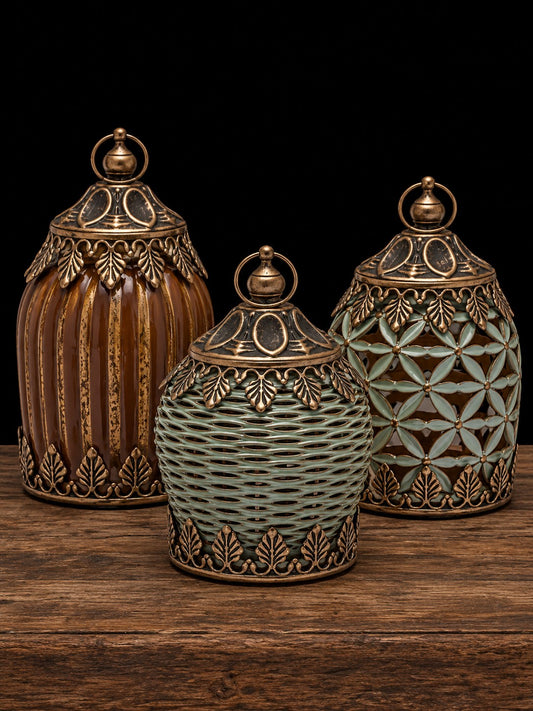 Tres faroles decorativos con acabado dorado envejecido, uno rayado caramelo y dos verdes, sobre mesa de madera rústica