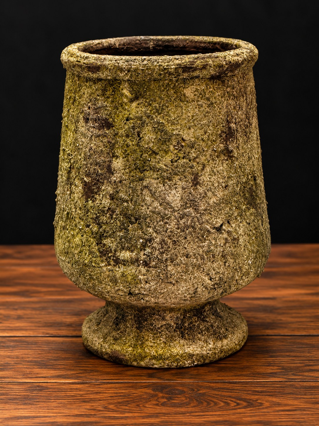 Jarrón copa de terracota con acabado efecto piedra y musgo en tonos verdes y arena sobre mesa de madera