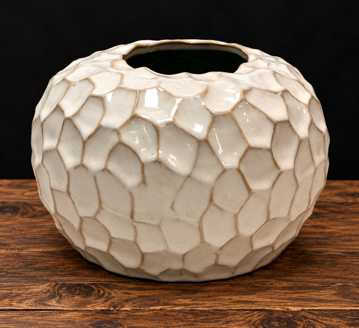 Jarrón redondo de cerámica esmaltada blanco roto con relieve de escamas sobre mesa de madera